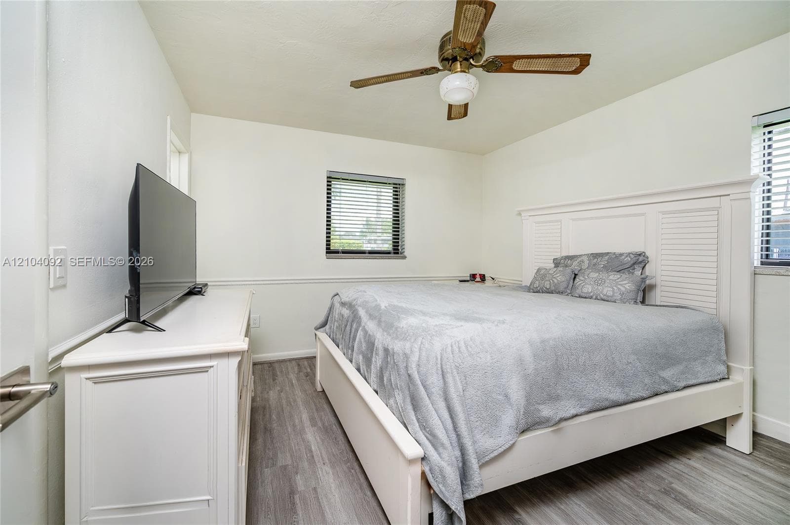 Wood-finish flooring, white wall wainscoting, and a ceiling-mounted fan with integrated light fixture
