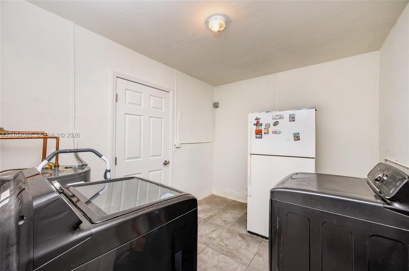 Utility space featuring neutral-toned tile flooring and a six-panel door