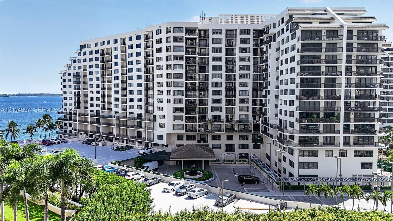 High-rise residential exterior featuring private balconies, integrated parking, a structured entry portico, and proximity to the waterfront