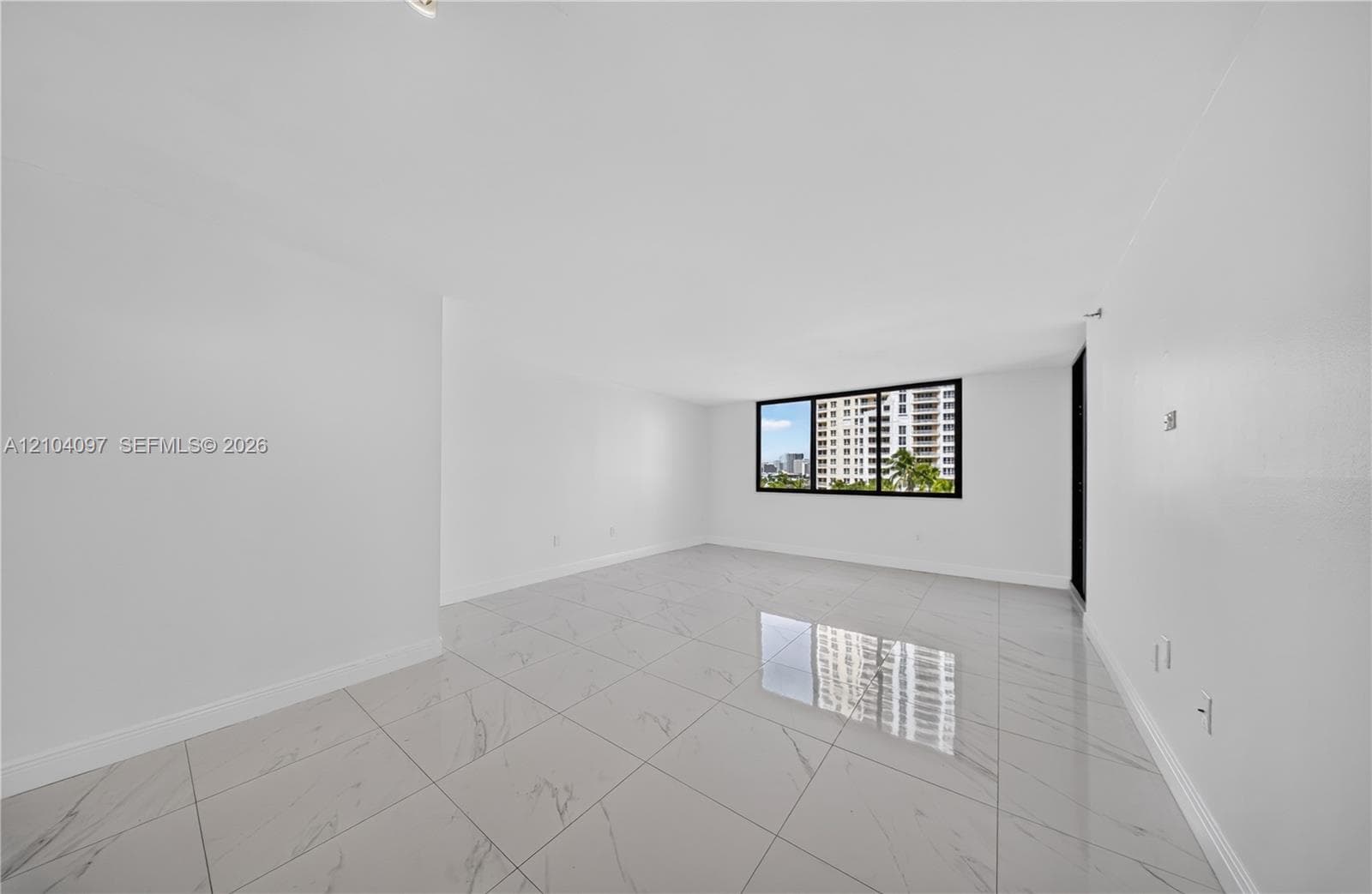 Open-concept interior featuring large-format tile flooring with marble-finish detailing and a black-framed window
