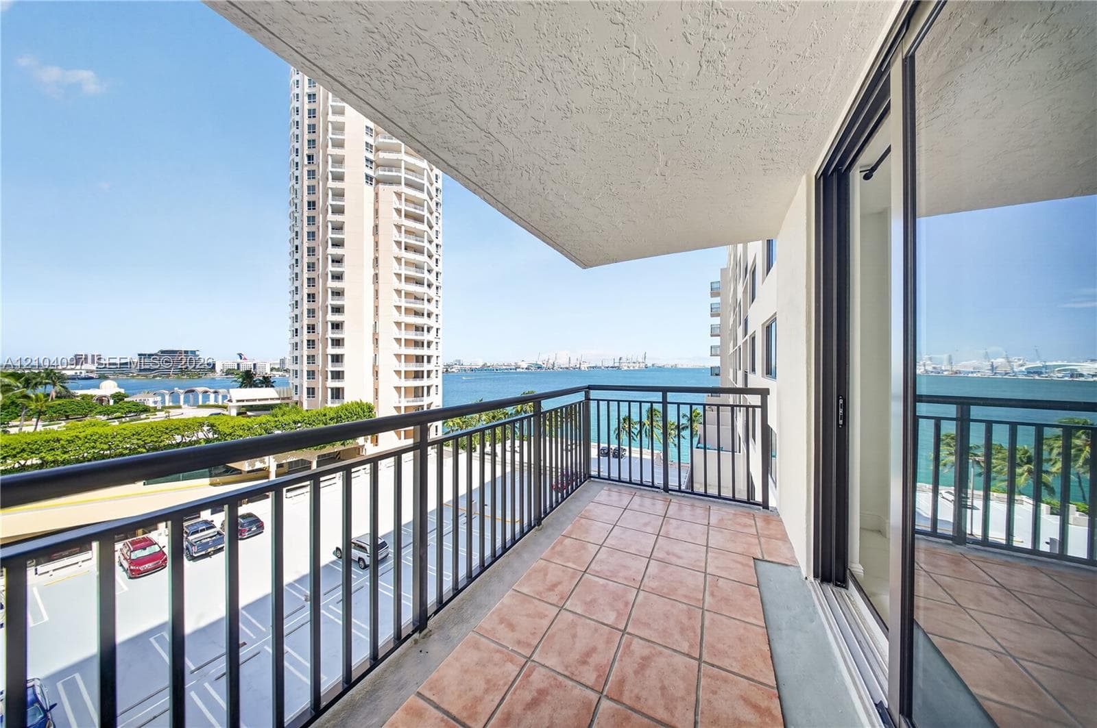Covered balcony featuring tile flooring and metal railings, accessible via full-height glass sliding doors