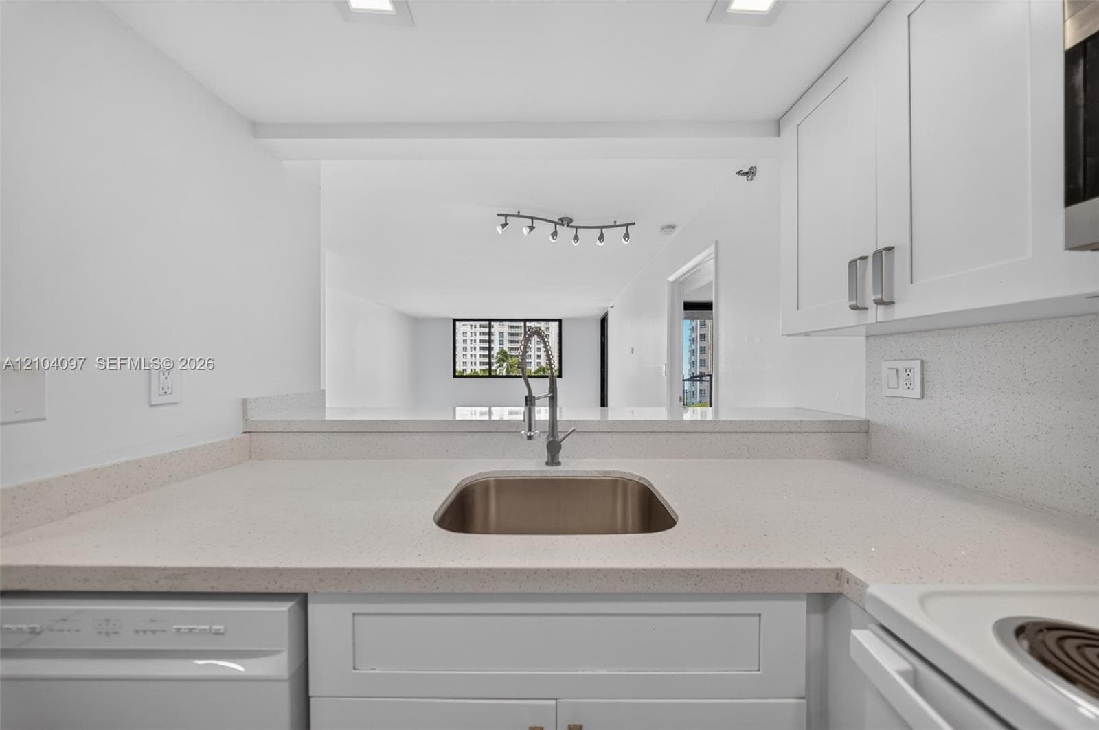 Kitchen featuring white cabinetry, solid surface countertops, stainless steel undermount sink with gooseneck faucet, and recessed ceiling lighting