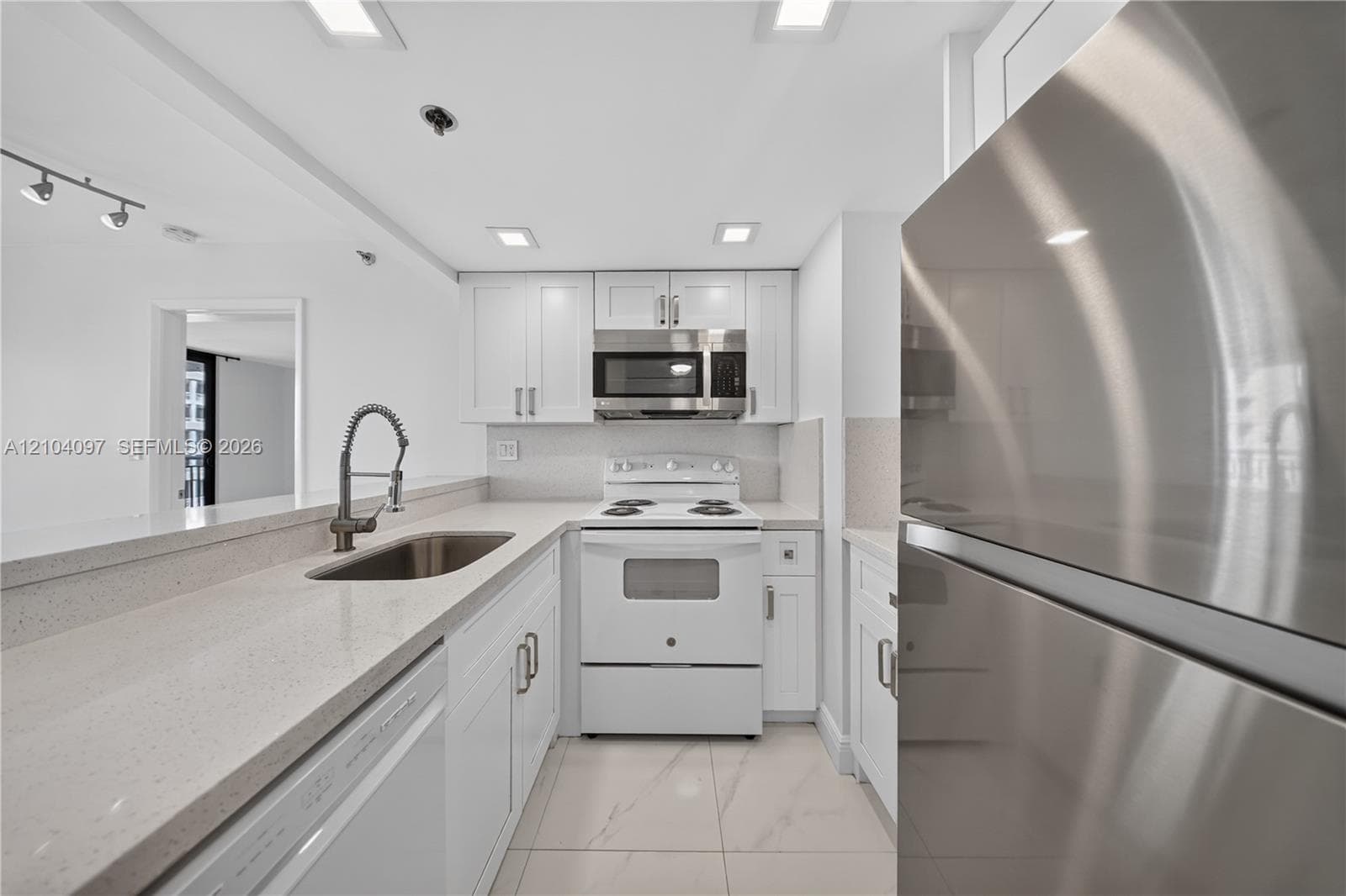 Kitchen featuring white cabinetry, solid surface countertops, stainless steel appliances, a pull-down kitchen faucet, and tile flooring