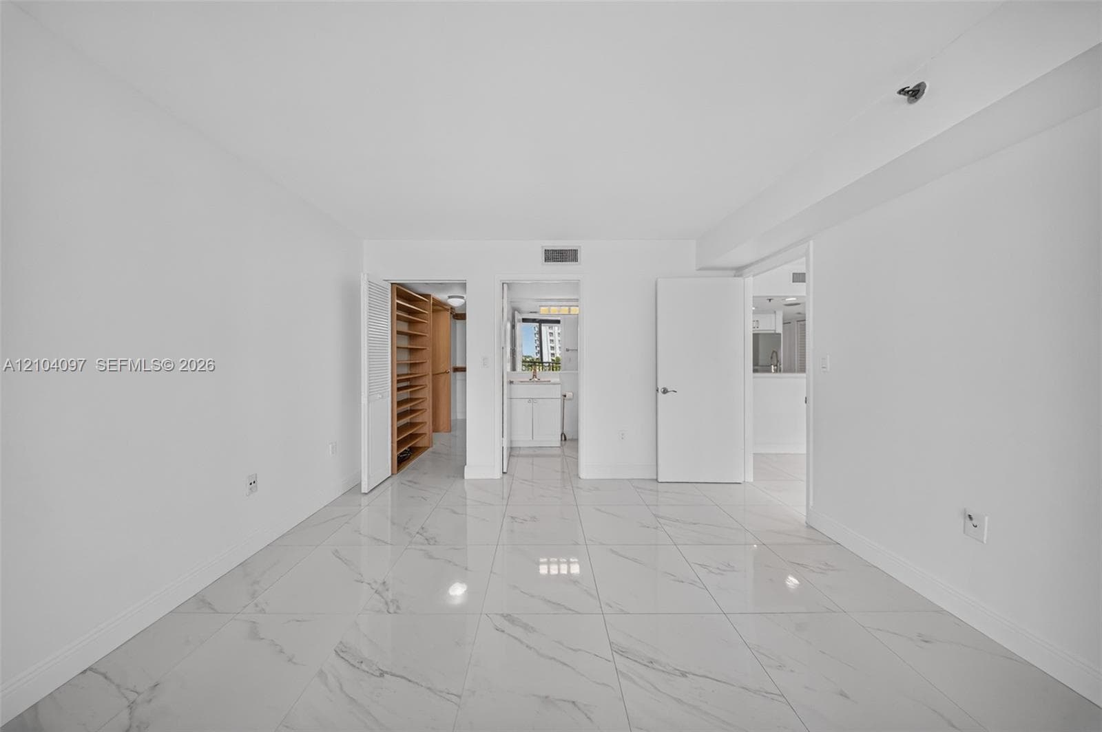 Large-format polished tile flooring, neutral wall finishes, built-in shelving, and white interior doors