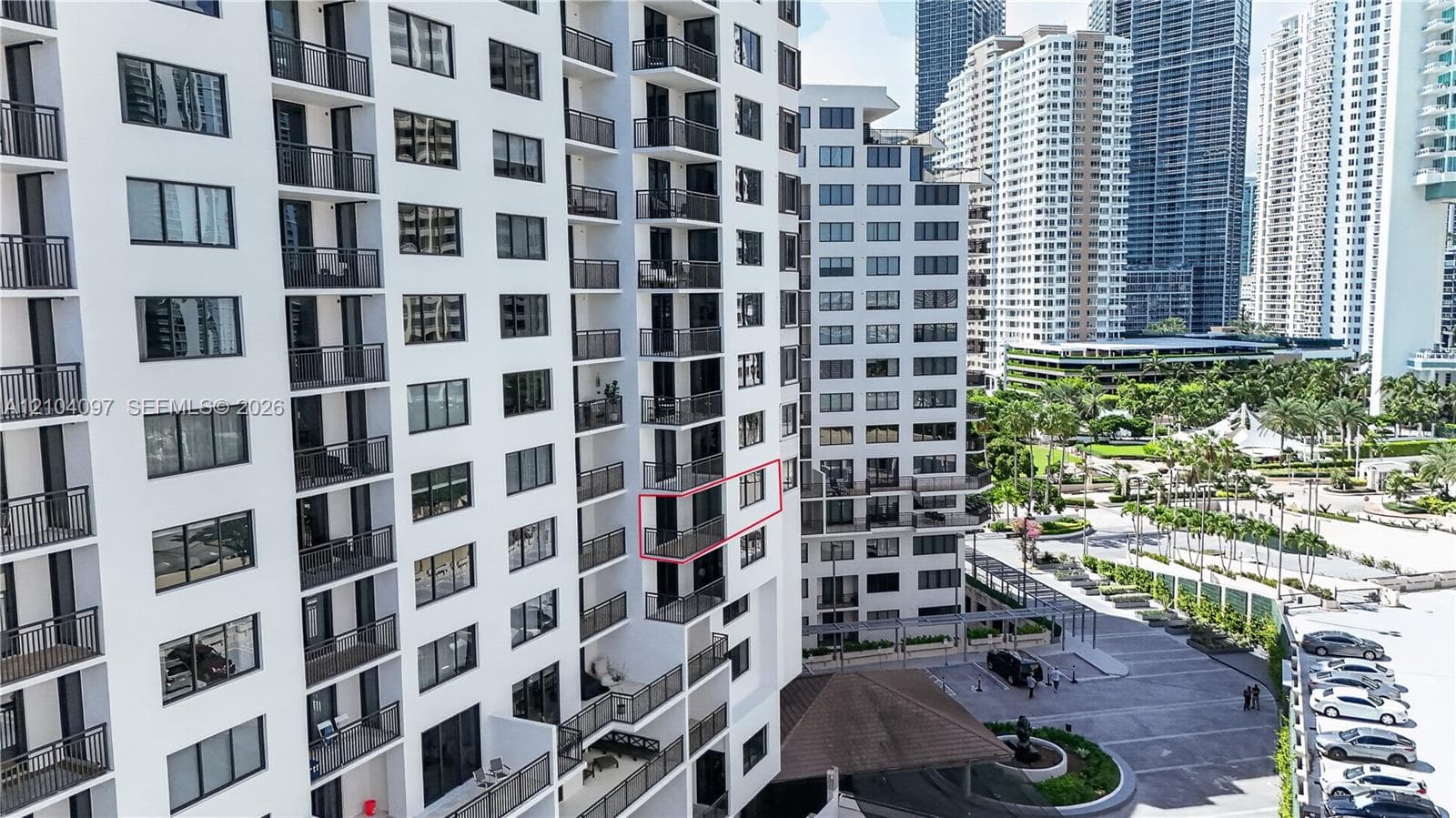 High-rise residential building featuring stacked private balconies, uniform multi-pane windows, and a paved exterior motor court