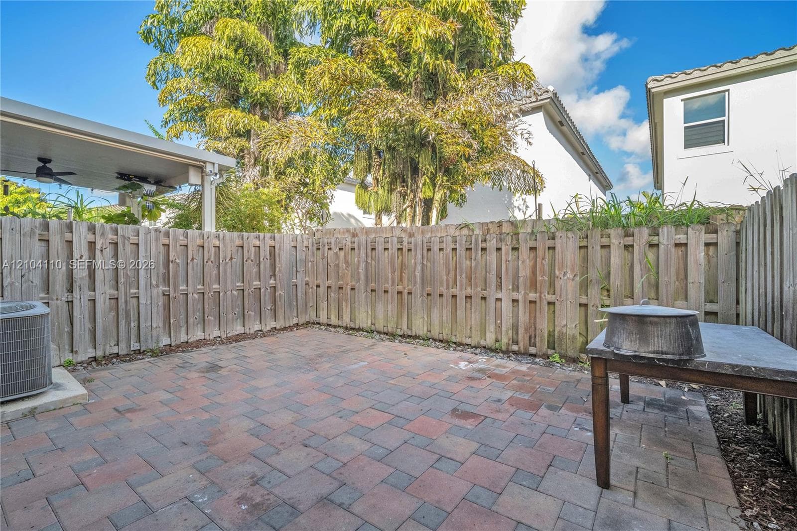 Paver patio with a wood privacy fence and covered outdoor ceiling fans