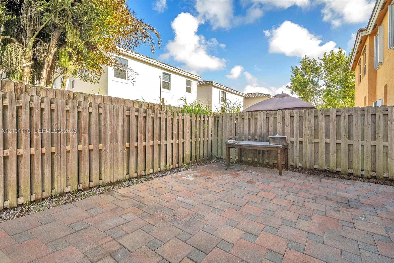 Paved patio area featuring multi-toned paver stones and a wood privacy fence