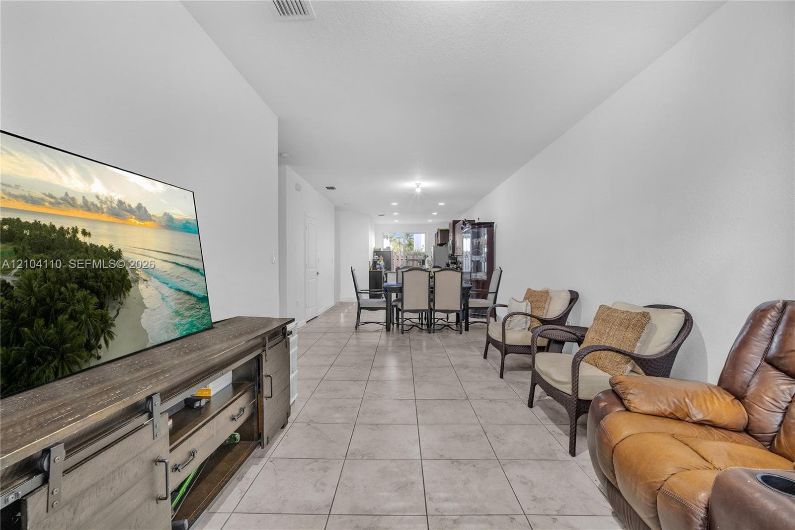 Open-concept living area with tile flooring throughout, white walls, and recessed lighting