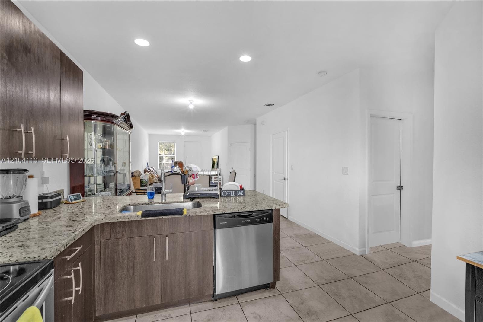 Kitchen featuring a U-shaped countertop, integrated stainless steel dishwasher, and wood-finish cabinetry