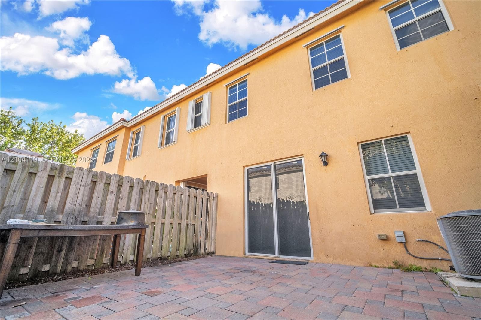 Private paved patio with wood fencing and sliding glass door entry