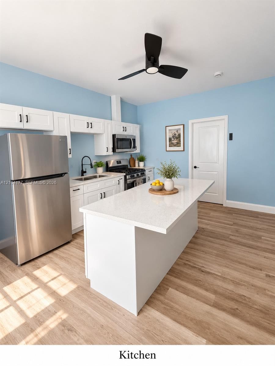 Kitchen featuring a central island with a solid surface countertop, white shaker-style cabinetry, stainless steel appliances, and wood-finish flooring
