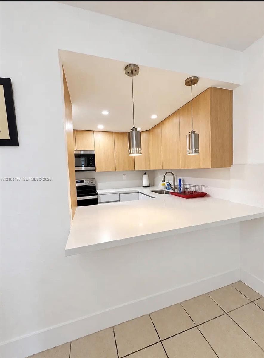 Bathroom featuring a wood-finish floating vanity, recessed ceiling lighting, a mirrored medicine cabinet, and large-format tile flooring