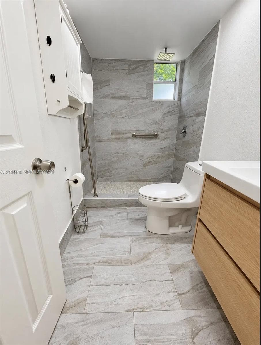 Interior space featuring neutral large-format tile flooring, white walls, two sets of white panel doors with brushed metal hardware, and a single vertical window