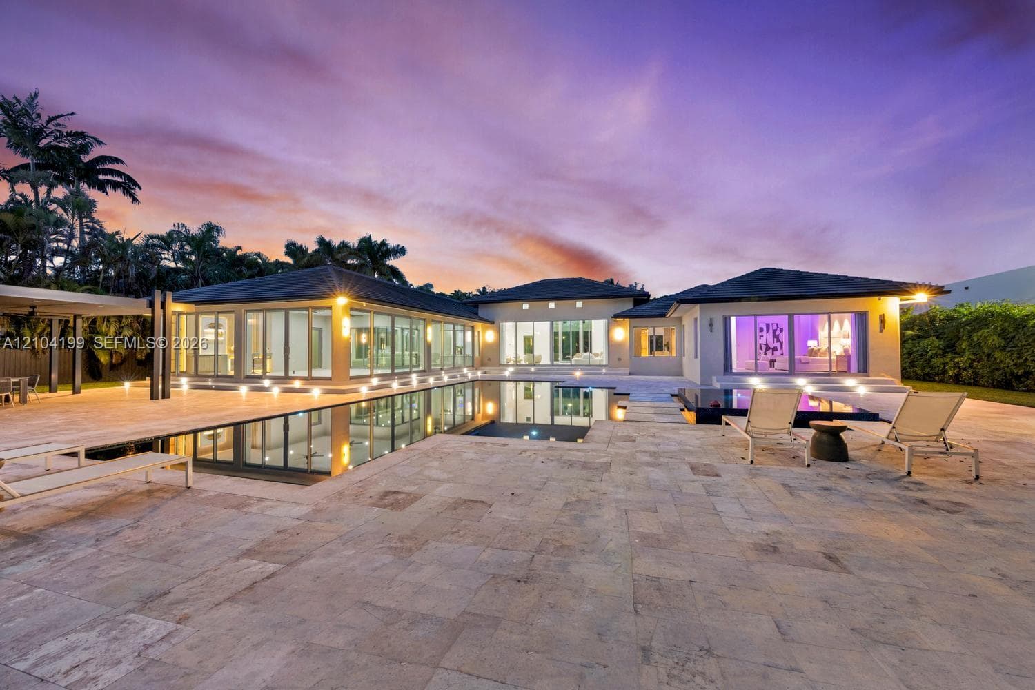 Expansive backyard featuring a manicured lawn, mature trees, and dense perimeter foliage