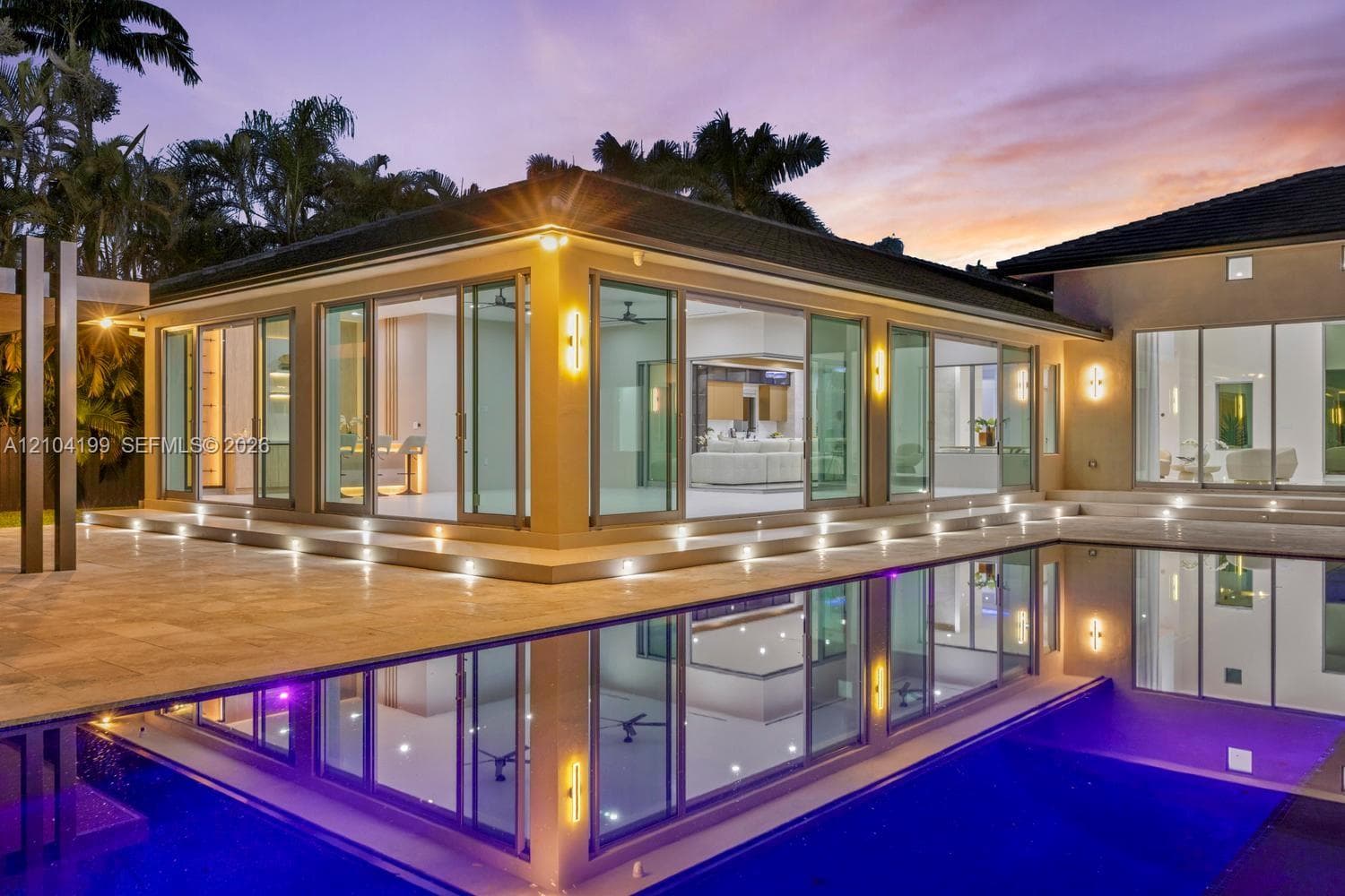 Covered outdoor patio featuring a slatted wood-finish ceiling, recessed lighting, ceiling fans, stone paver flooring, and a swimming pool