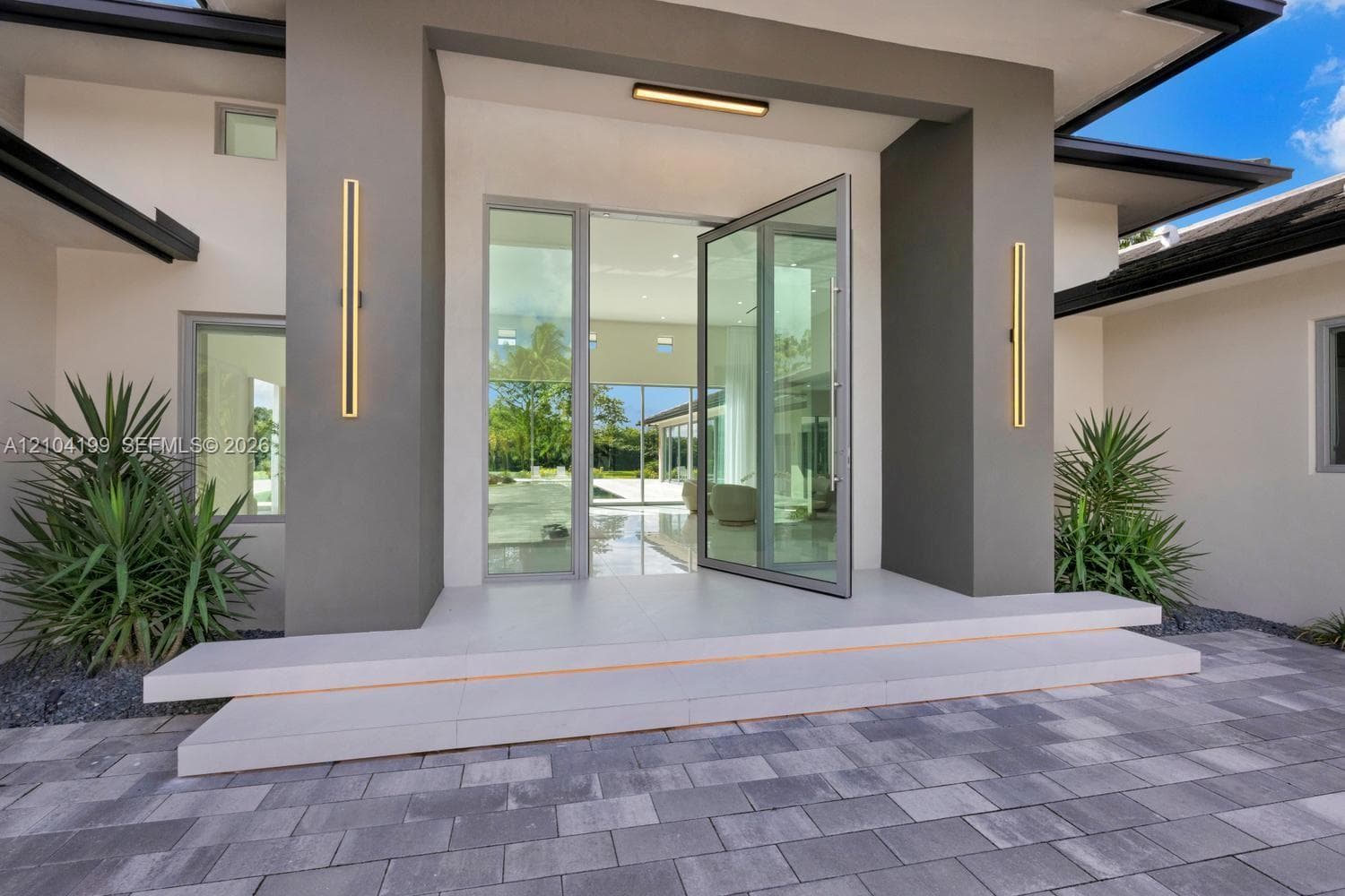 In-ground pool featuring a stone-tile deck, expansive glass sliding doors, and a covered patio area