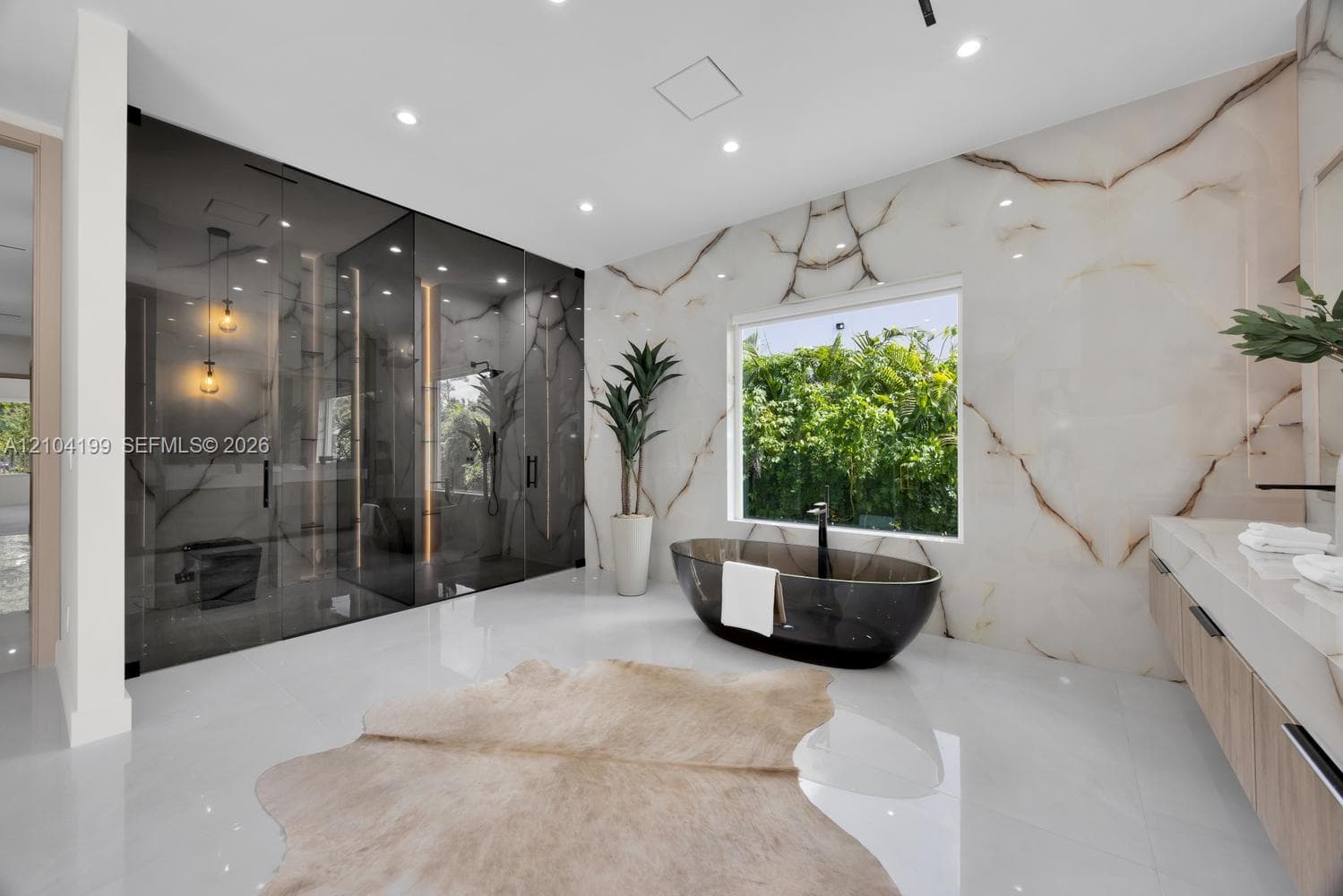 Custom built-in wood-finish cabinetry with full-height glass doors, integrated vertical LED accent lighting, central storage island with glass-top display, and built-in vanity station