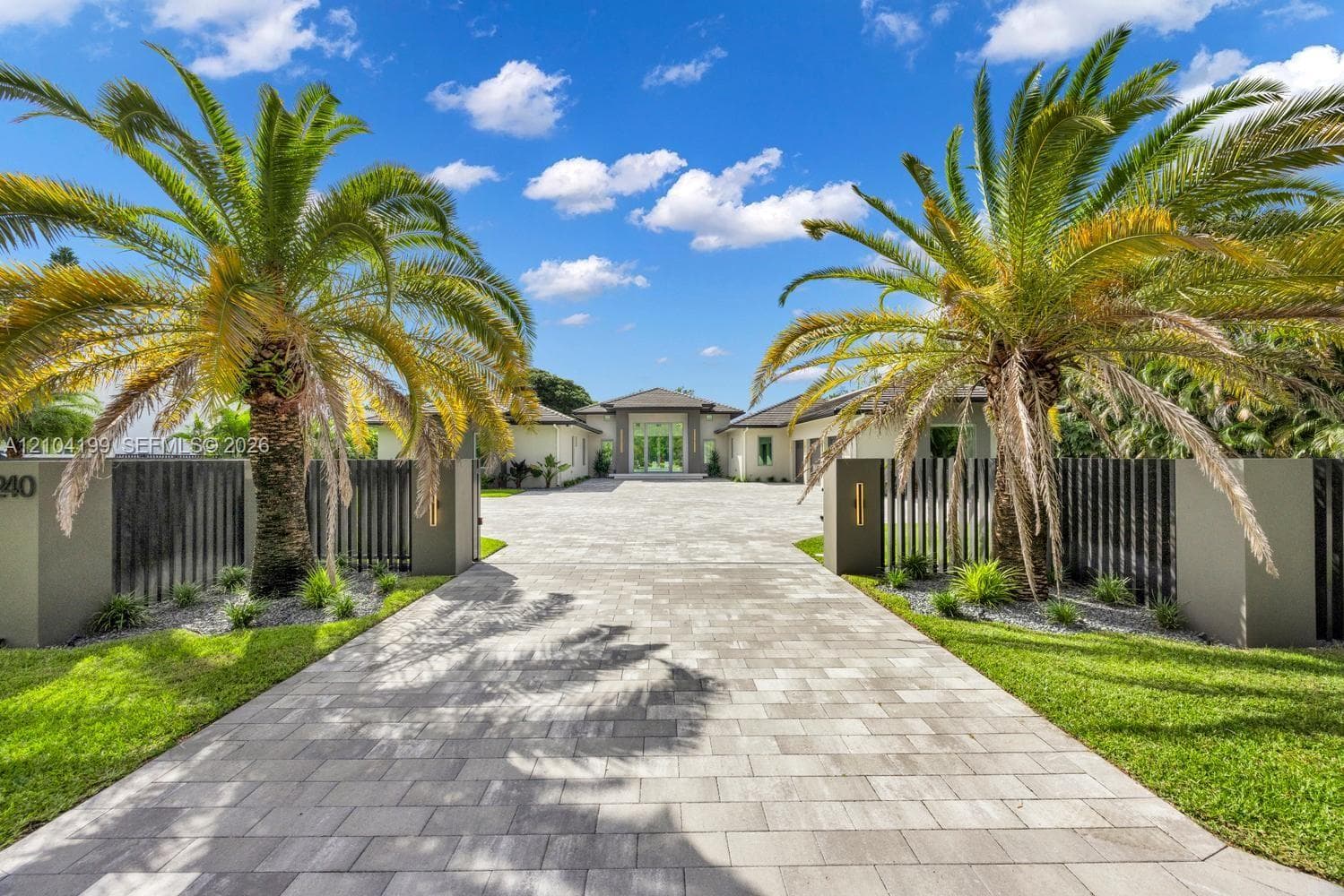 Single-story estate featuring a multi-car garage, a paver driveway, light-toned exterior finish, and a covered entryway