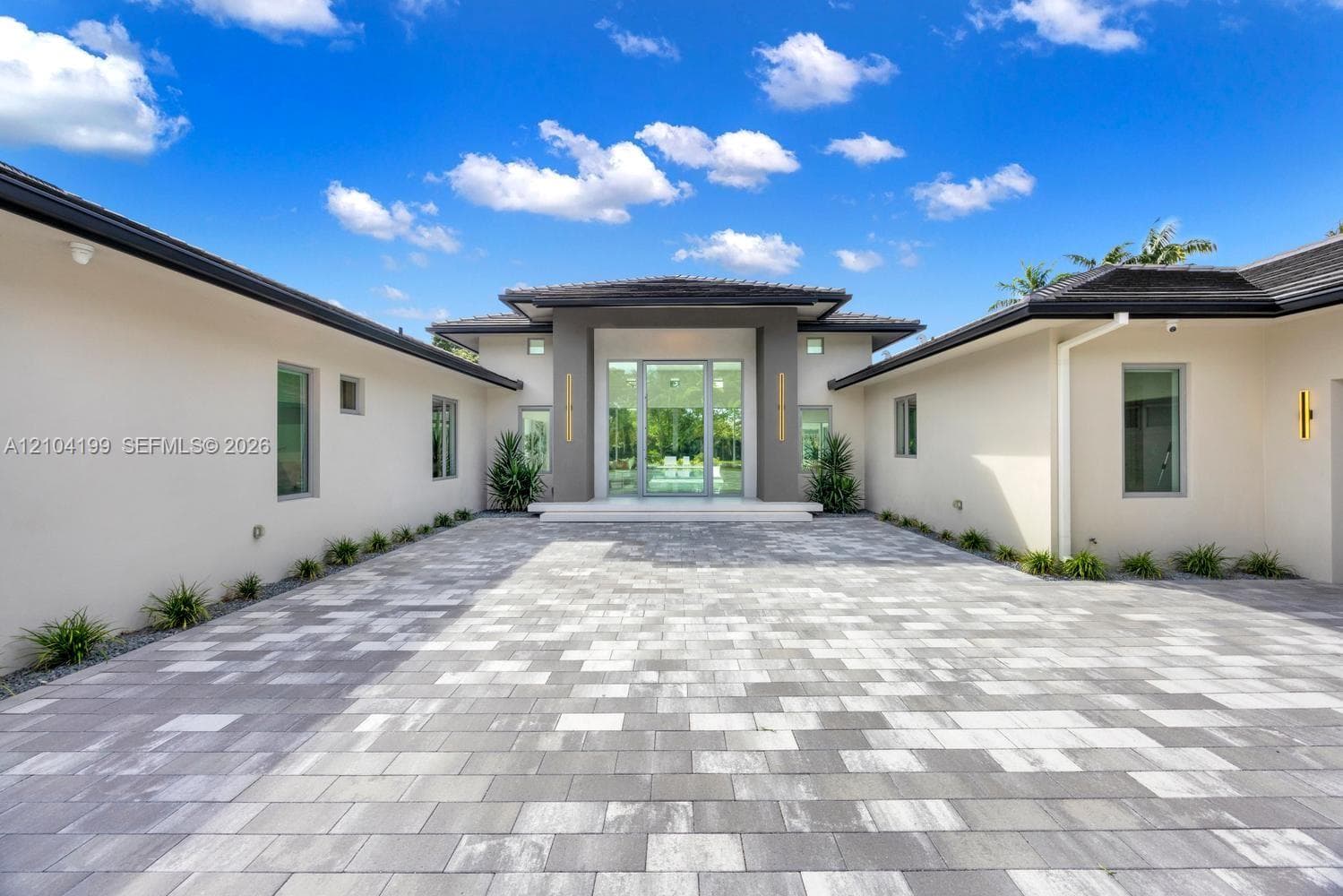 Outdoor living space featuring an expansive stone patio, a rectangular swimming pool, an attached spa, and floor-to-ceiling glass panel doors