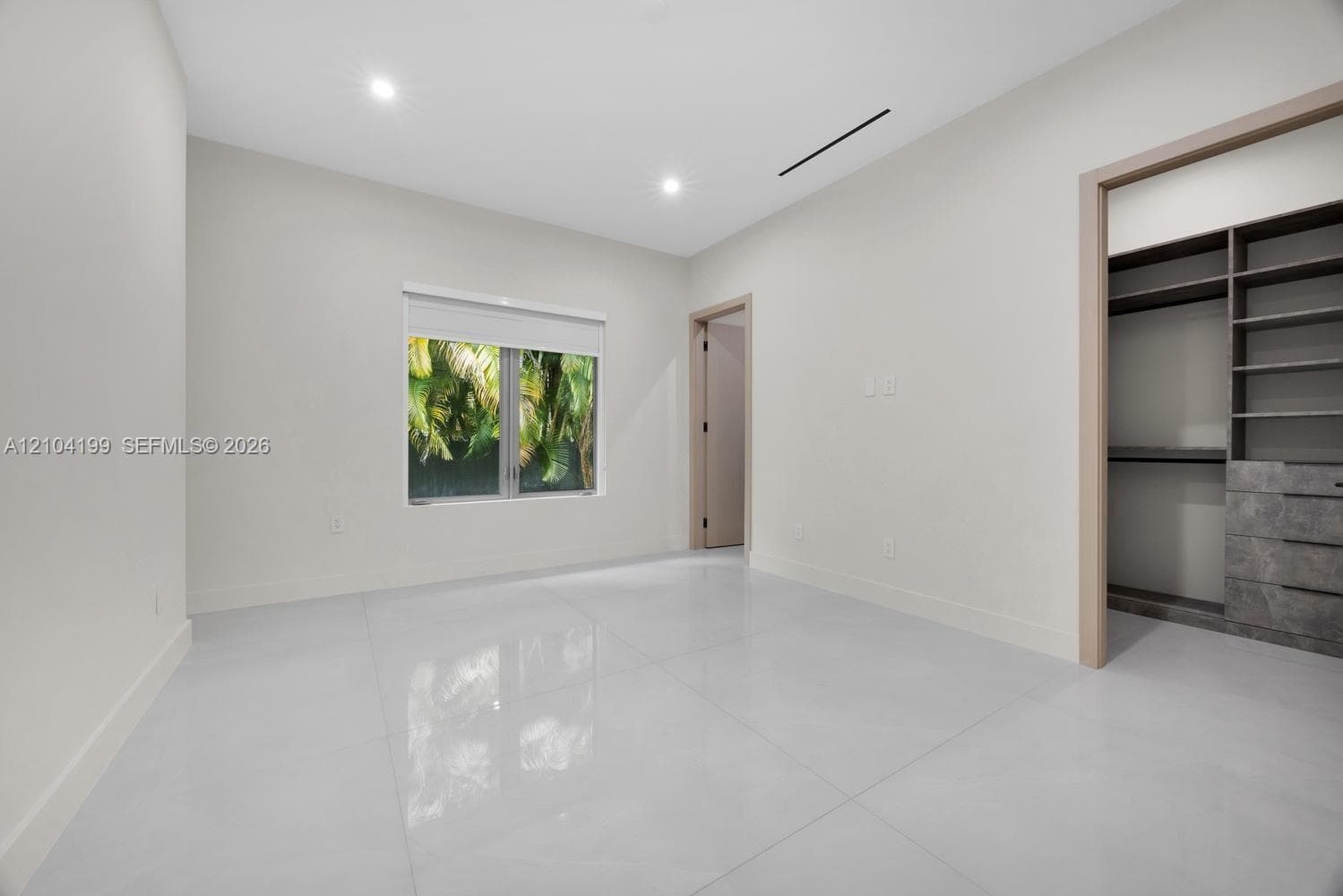 Three-car garage featuring a speckled epoxy-coated floor, bright LED panel lighting, and three sectional garage doors with frosted windows