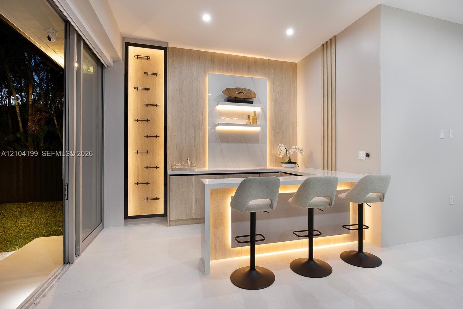 Bathroom featuring a wall-mounted floating vanity with a stone countertop, backlit organic-shaped mirror, matte black fixtures, and a walk-in shower with floor-to-ceiling tile