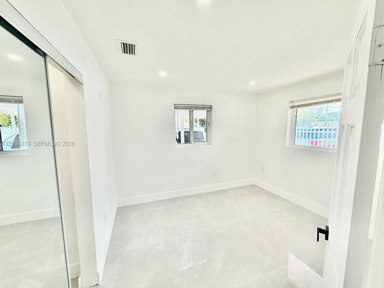 Recessed lighting illuminates the white walls and light-toned tile flooring