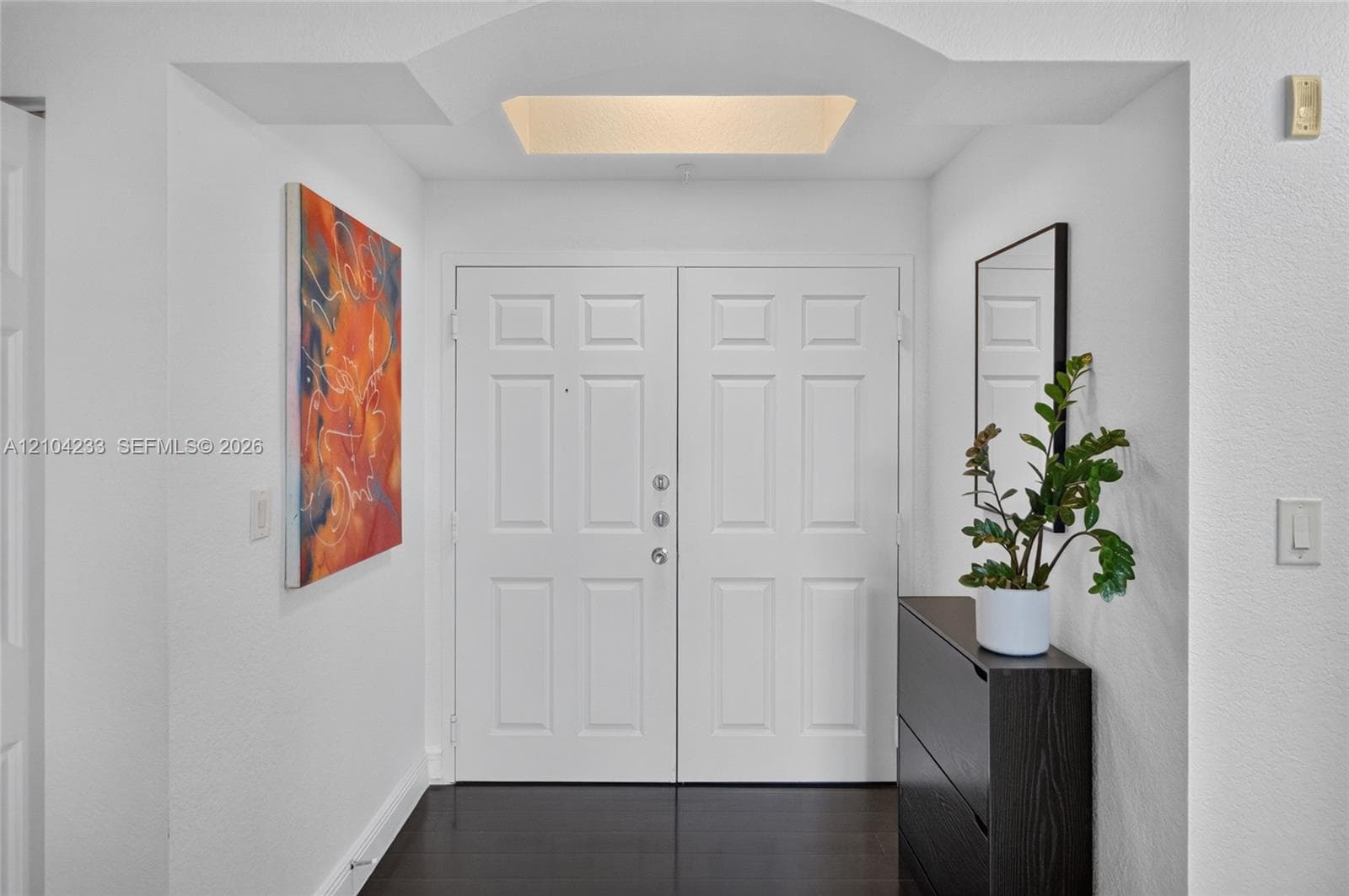Entryway featuring double doors, recessed ceiling architecture, and dark wood-finish flooring