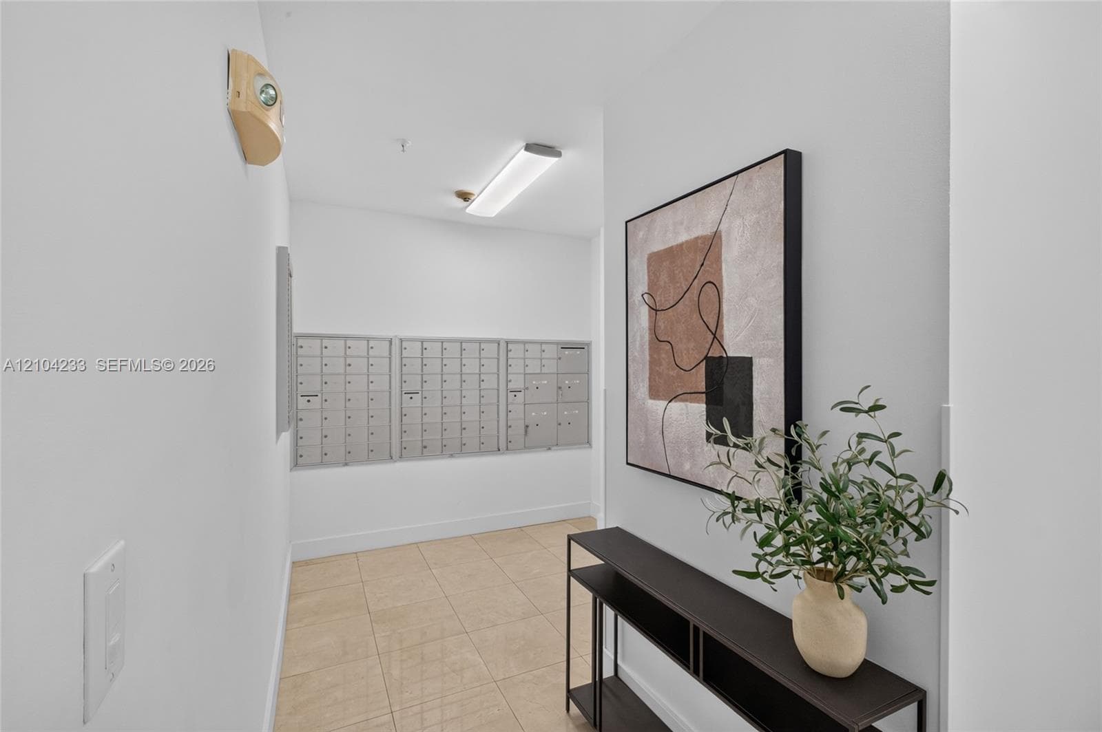 Mail center featuring metallic parcel lockers, neutral ceramic tile flooring, and overhead LED lighting