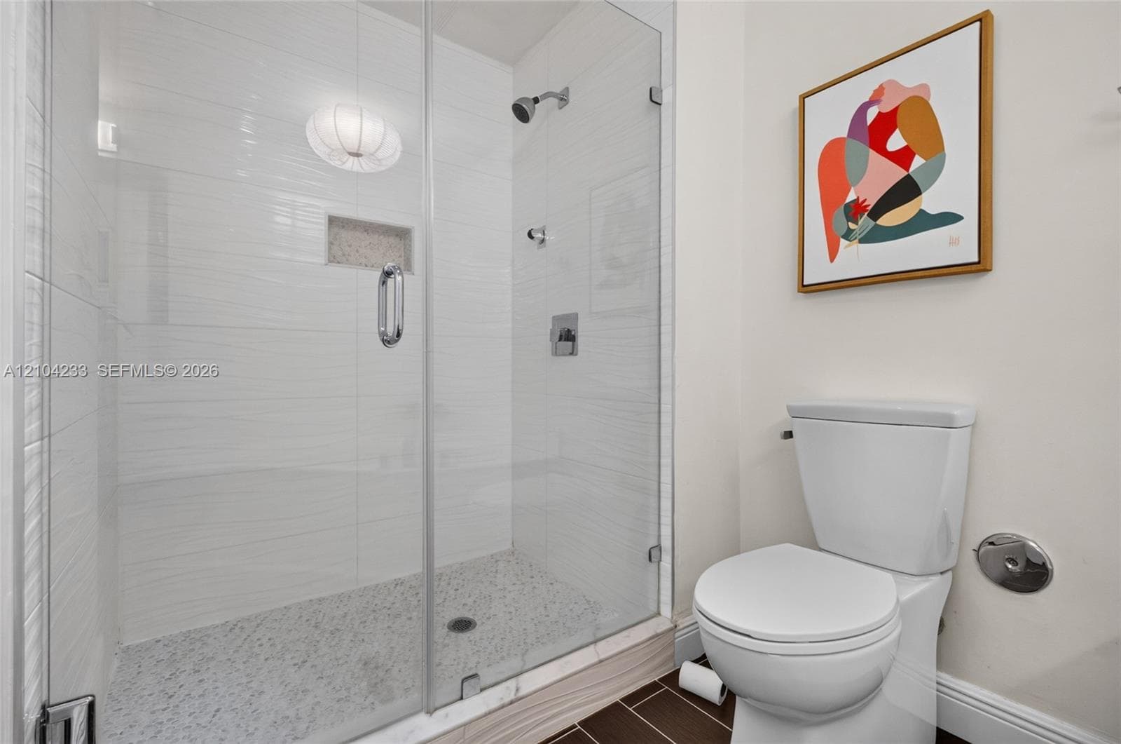 Walk-in shower featuring a frameless glass enclosure, textured horizontal wall tile, stone-composite flooring, and a recessed shower niche