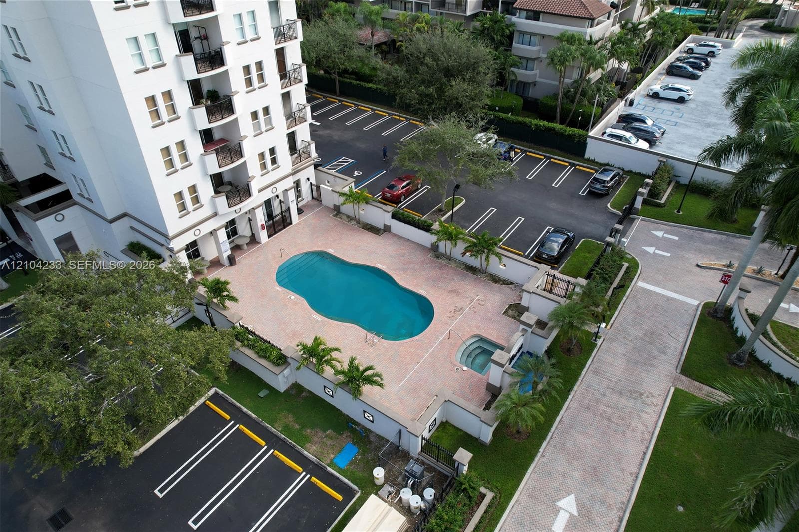 Multi-story exterior featuring a paved pool deck, custom-shaped swimming pool, attached spa, and structured parking area
