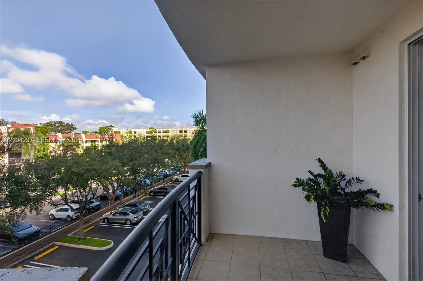Covered balcony featuring tile flooring and a black metal railing