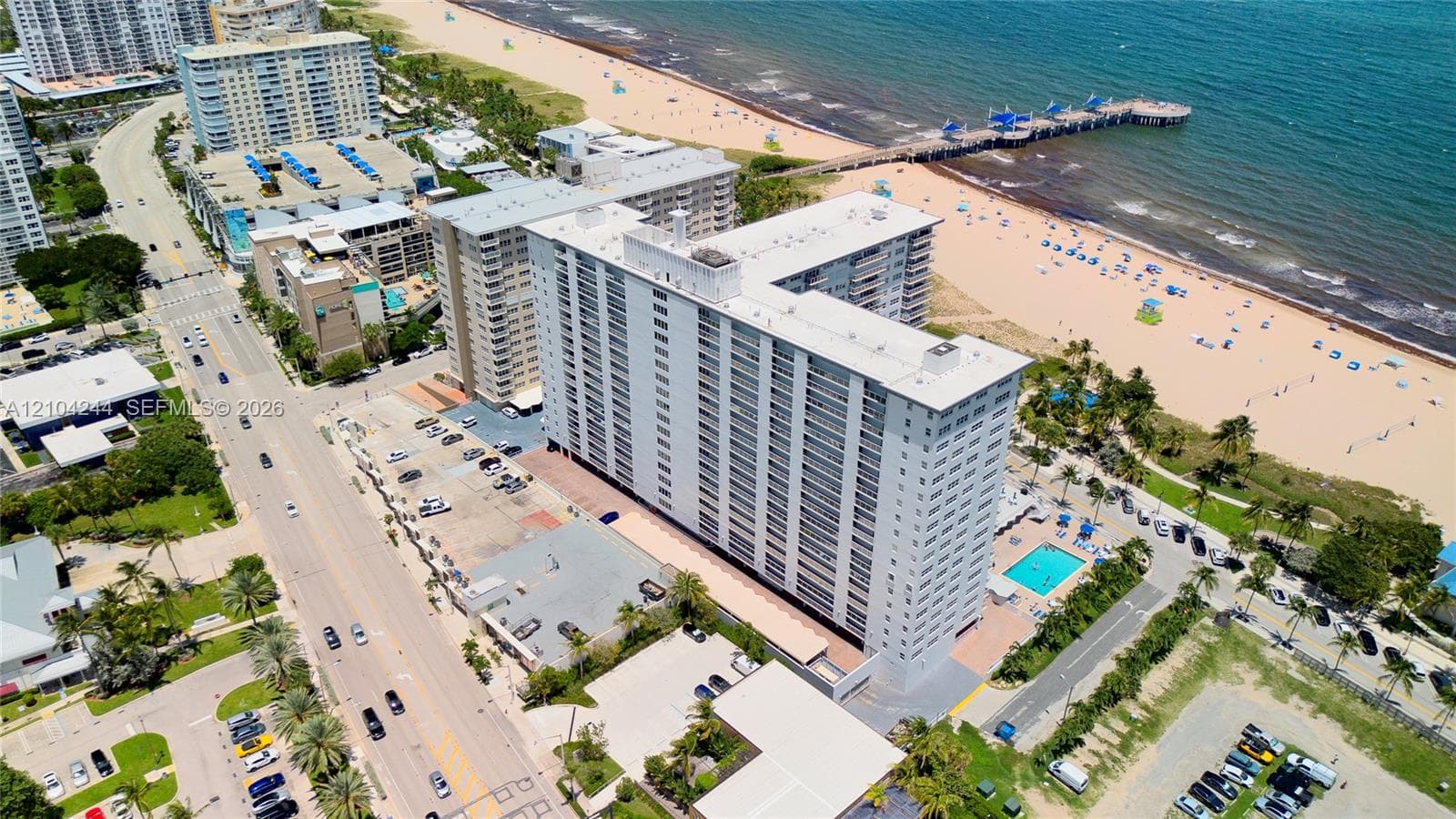 High-rise condominium building featuring direct oceanfront positioning, an outdoor swimming pool, and gated surface parking
