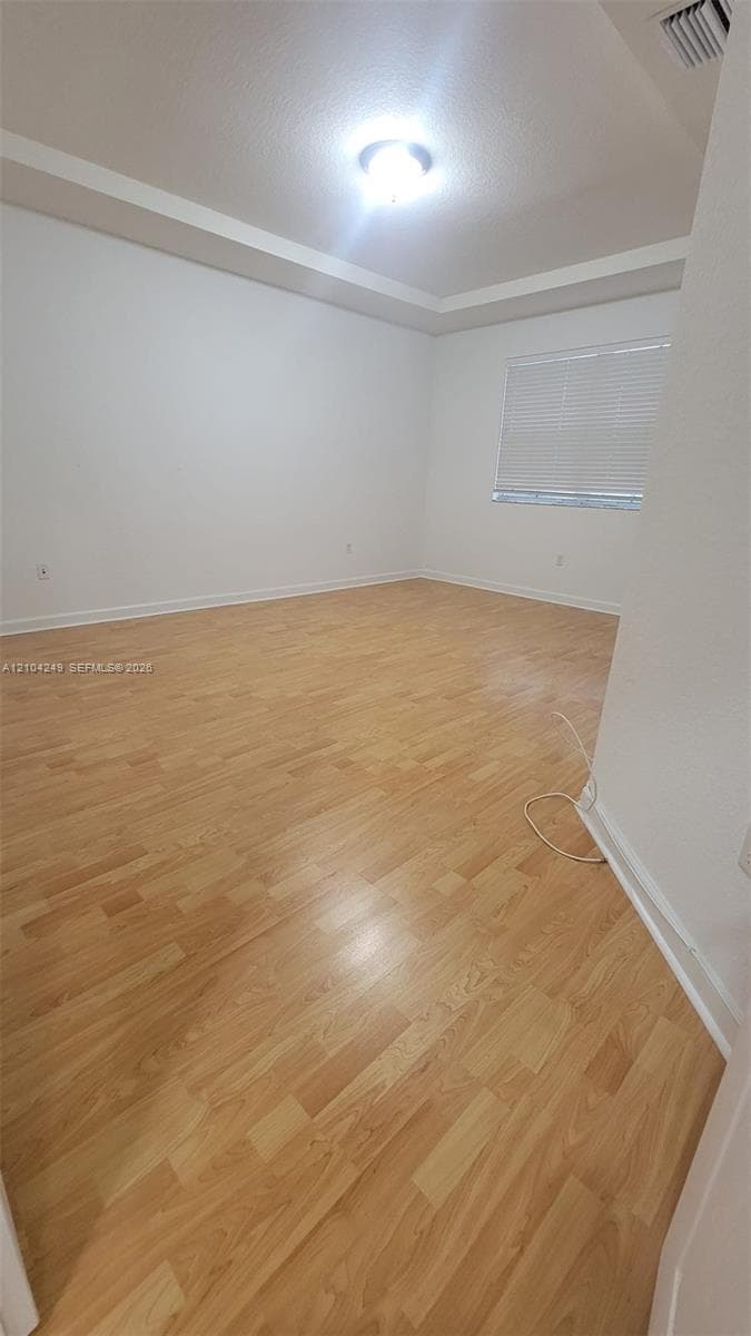 Master Bedroom featuring wood-finish flooring, tray ceiling, and neutral wall paint