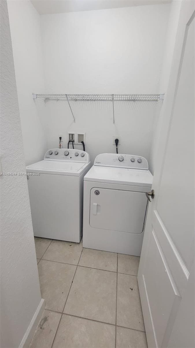 Dedicated utility space featuring neutral tile flooring, white walls, and built-in overhead wire shelving