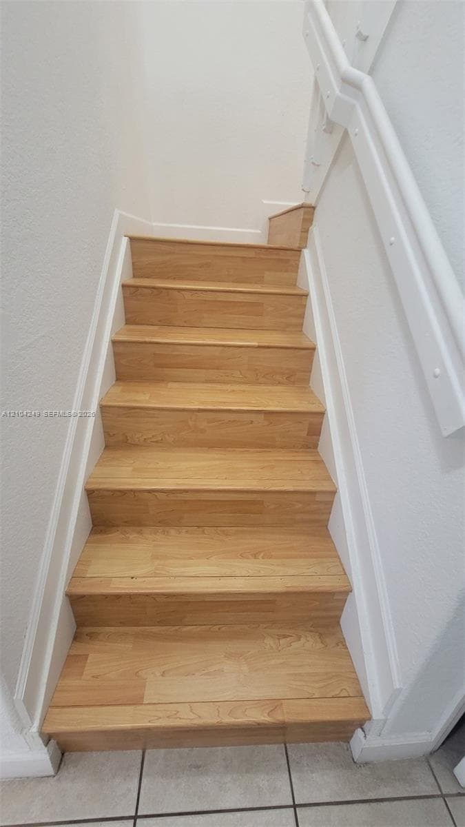 Staircase featuring wood-finish treads and a painted white handrail
