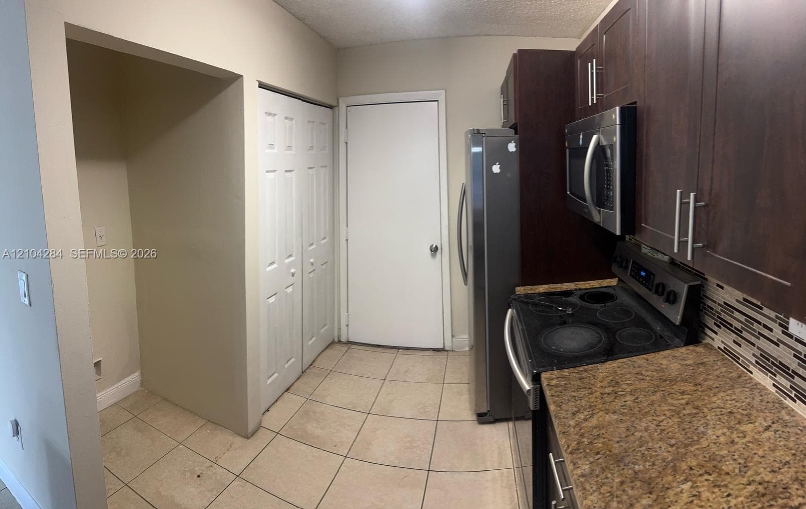 Neutral-toned interior space featuring ceramic tile flooring, two windows with horizontal blinds, and a semi-flush mount ceiling fixture
