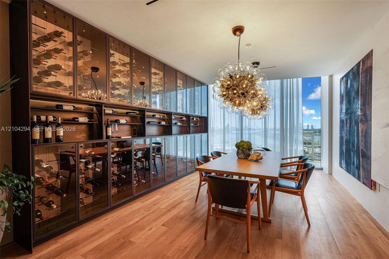 Built-in wine storage cabinetry with glass-front doors, wood-finish flooring, full-height windows, and a contemporary chandelier