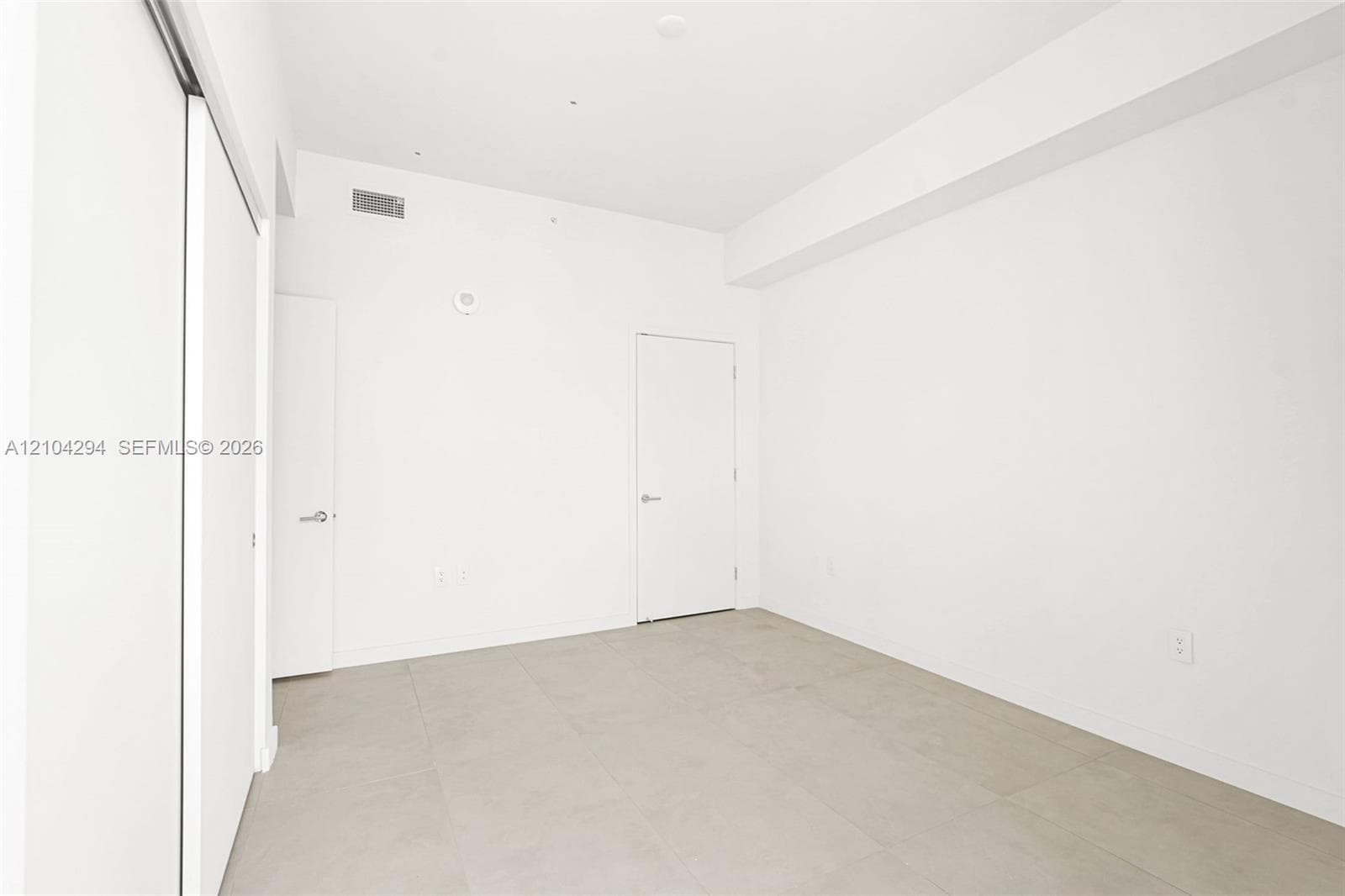 Neutral white wall finishes, light-toned tile flooring, recessed ceiling lighting, and sliding closet doors