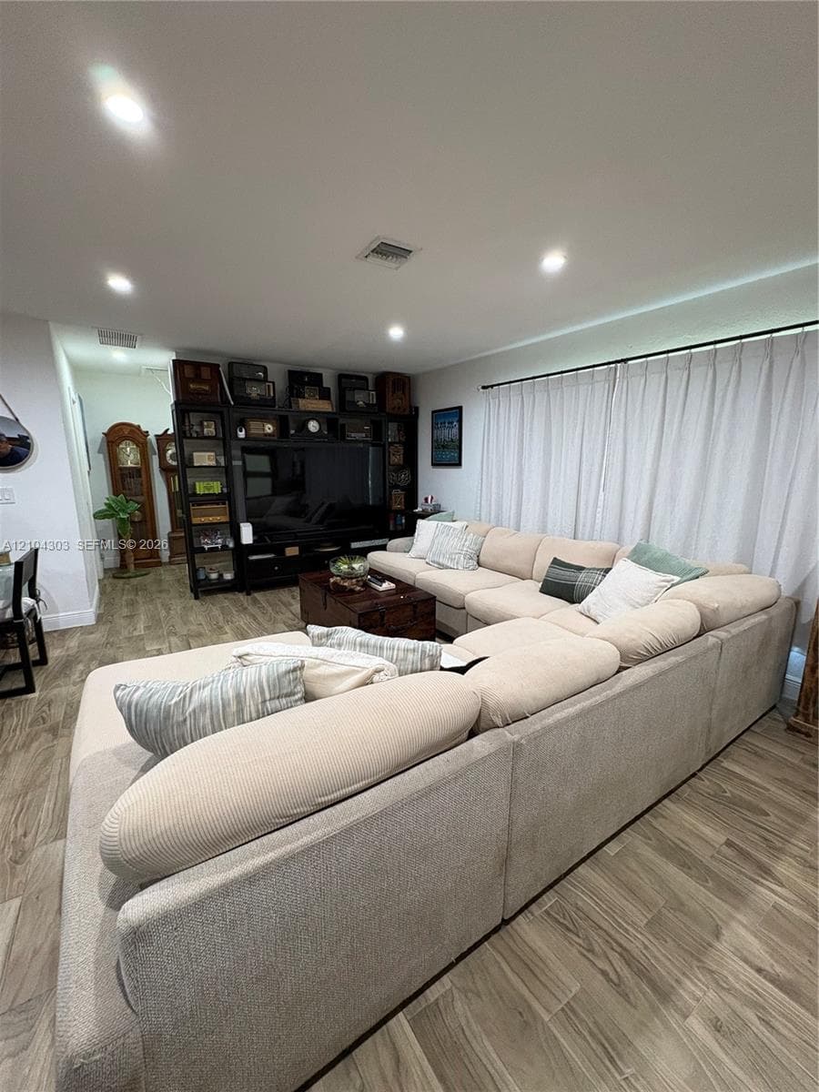 Living area featuring wood-finish flooring, recessed lighting, and built-in floor-to-ceiling cabinetry