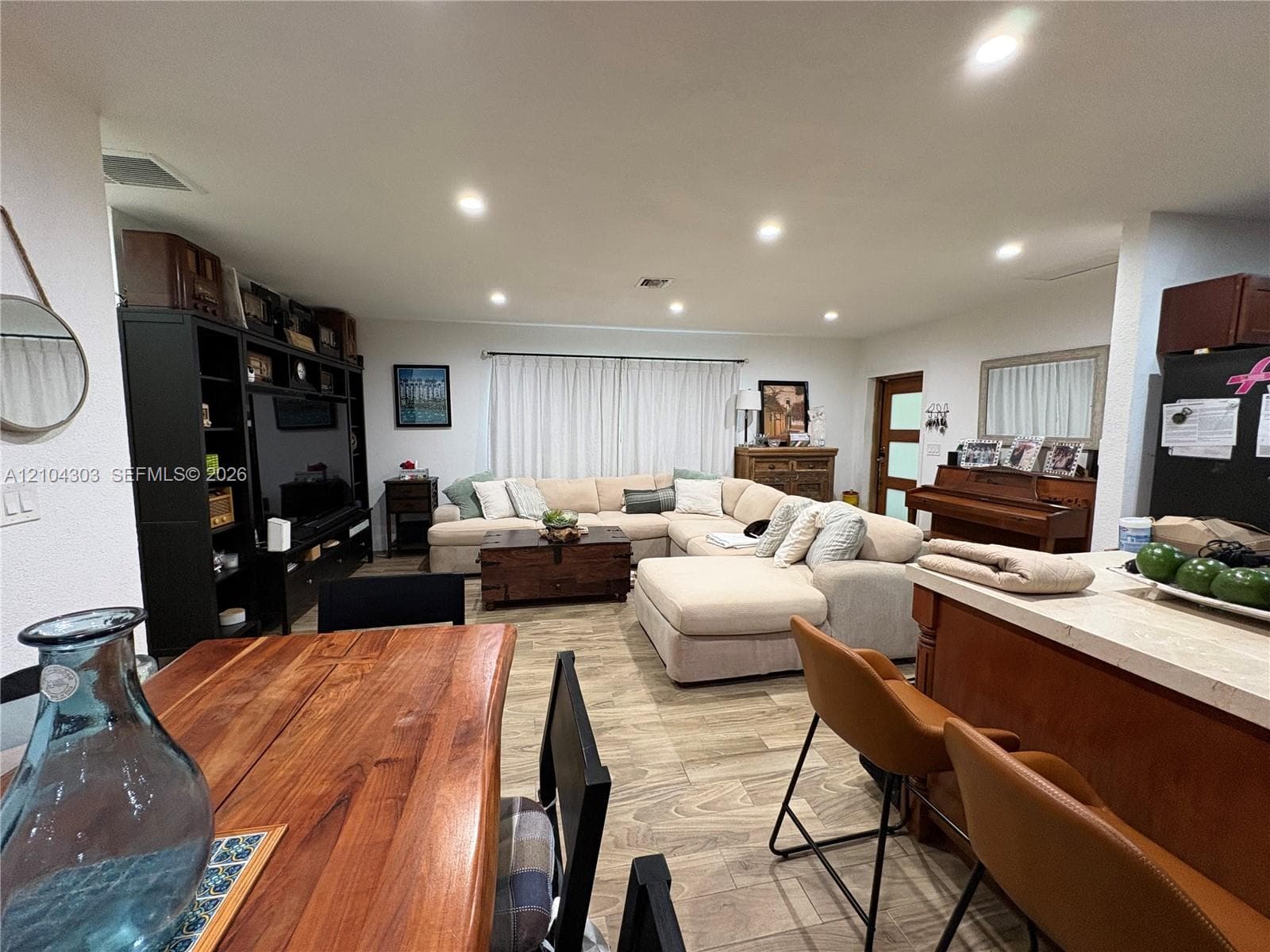 Open-concept area featuring wood-finish flooring, recessed lighting, and a kitchen island with a stone-top surface