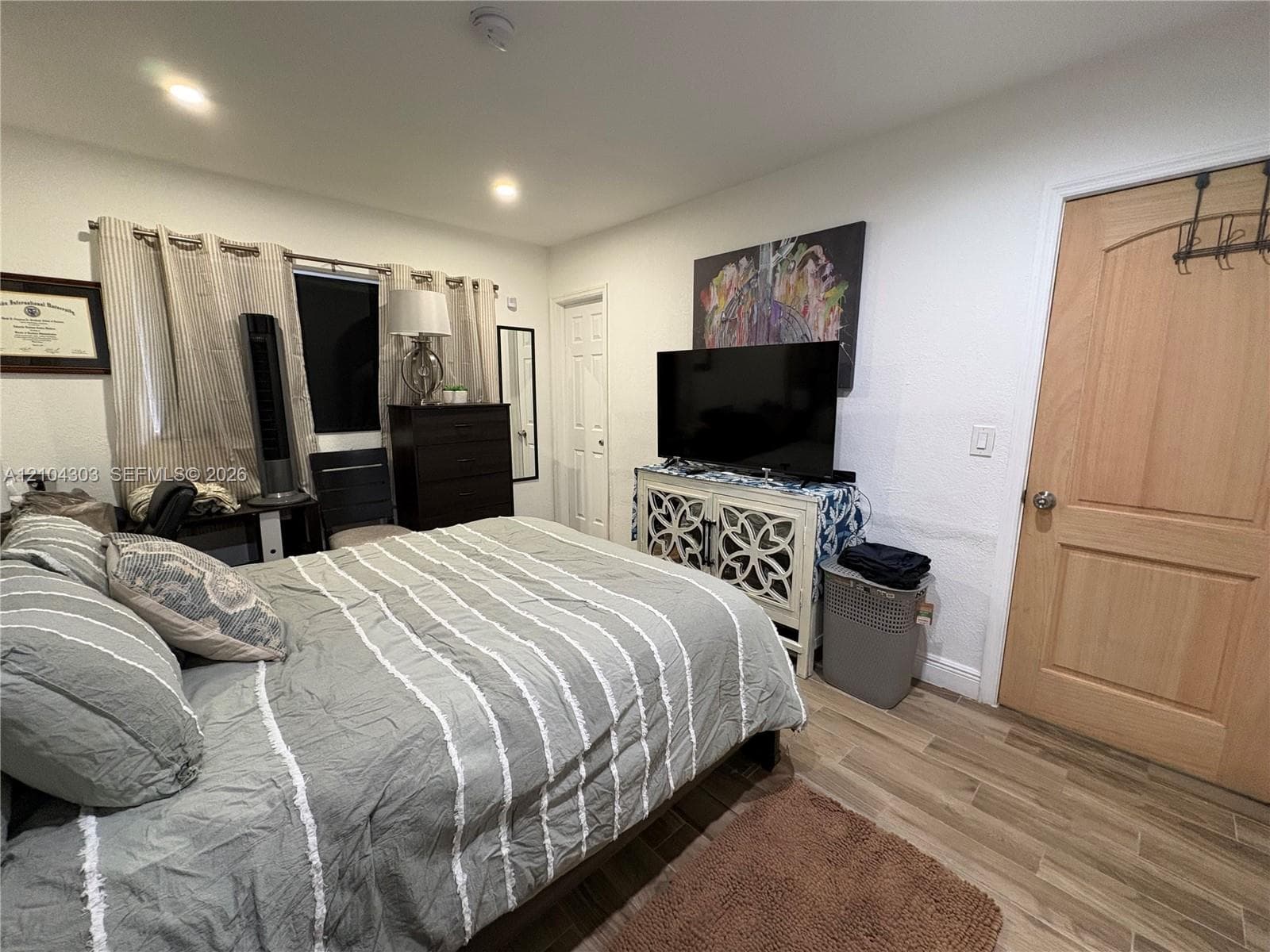 Room featuring wood-finish flooring, recessed lighting, and a solid wood interior door with a brushed nickel handle