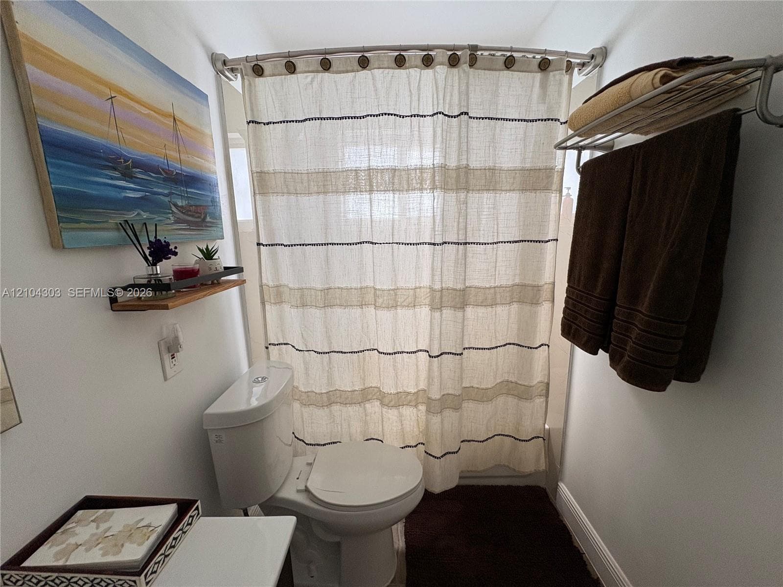 Bathroom featuring a wall-mounted towel rack and a curved shower curtain rod