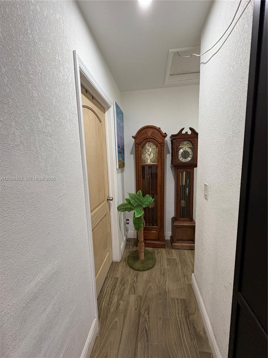 Hallway featuring textured wall finishes, wood-finish flooring, and a single-panel arch-top interior door