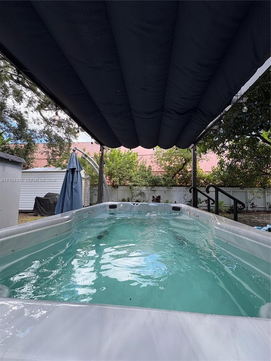 Built-in resistance pool featuring a retractable overhead canopy, integrated steps with black handrails, and surrounding privacy fencing