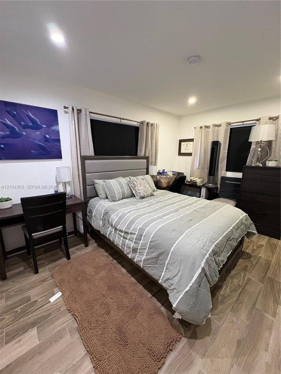 Wood-finish plank flooring, recessed lighting, and dual windows with metal hardware
