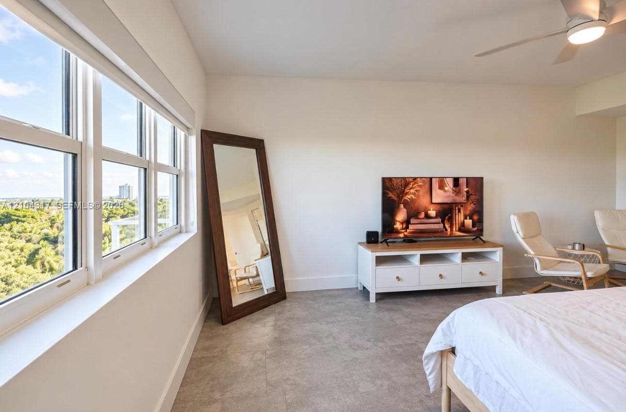 Large windows with multi-pane configuration, neutral-tone tile flooring, and a ceiling-mounted light fixture with fan
