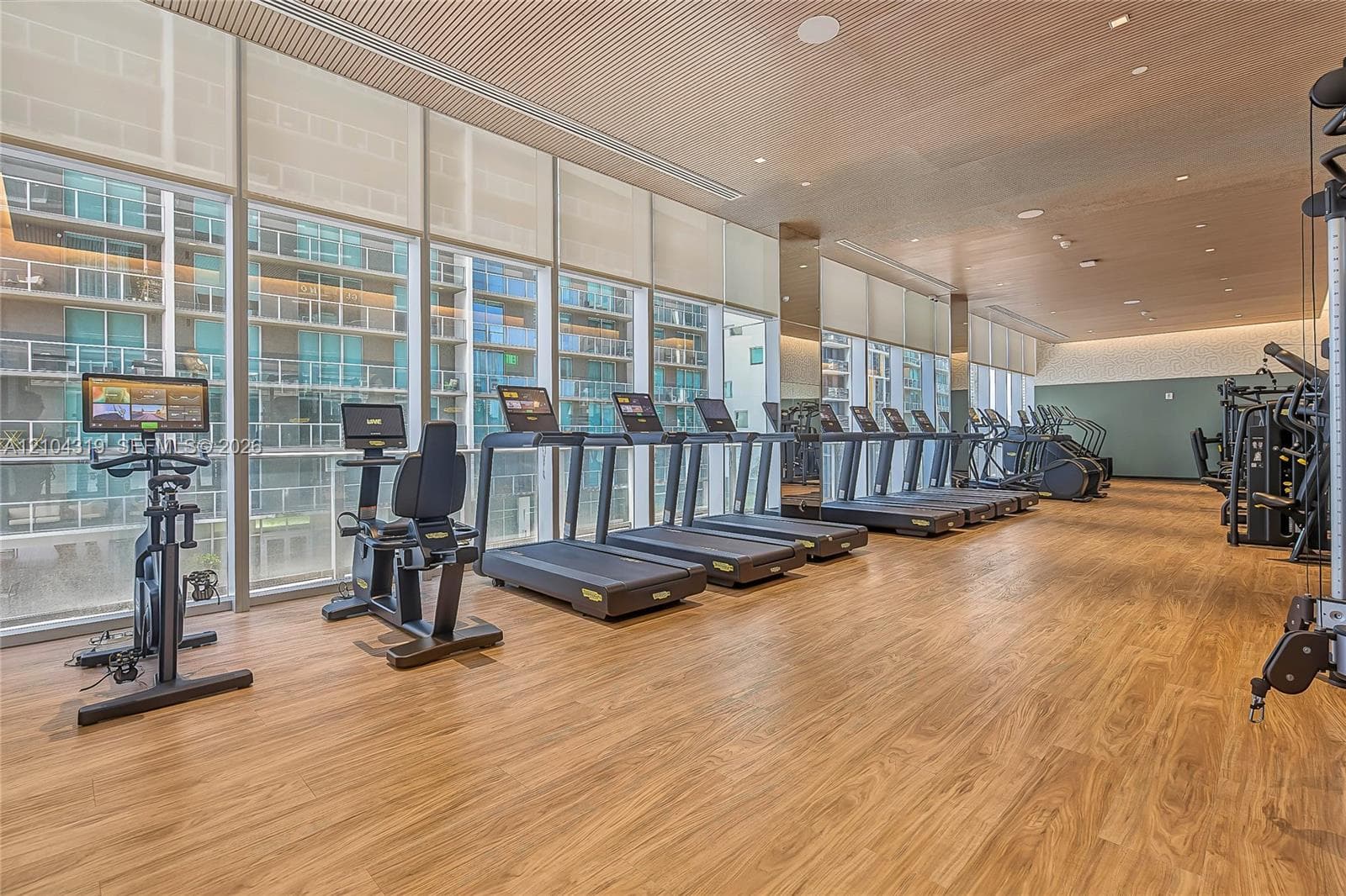 Fitness facility featuring wood-finish flooring, floor-to-ceiling windows, and recessed lighting