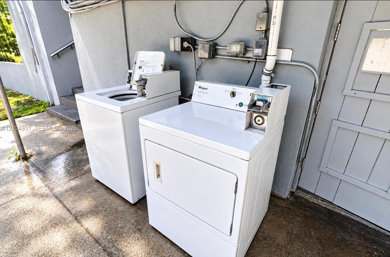 Coin-operated laundry area featuring a white top-loading washing machine and a matching front-loading dryer on a concrete surface