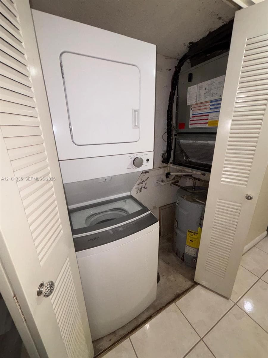 Laundry closet featuring a stackable washer and dryer, interior water heater, and HVAC unit, enclosed by louvered doors