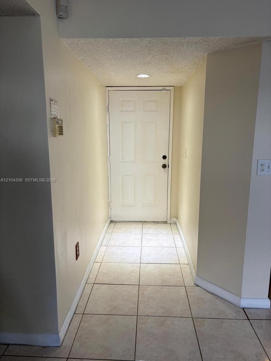 Entryway featuring square ceramic tile flooring, a six-panel door, and recessed ceiling lighting